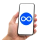 ruka držící telefon, na kterém je znak pro nekonečno, obrácená osmička